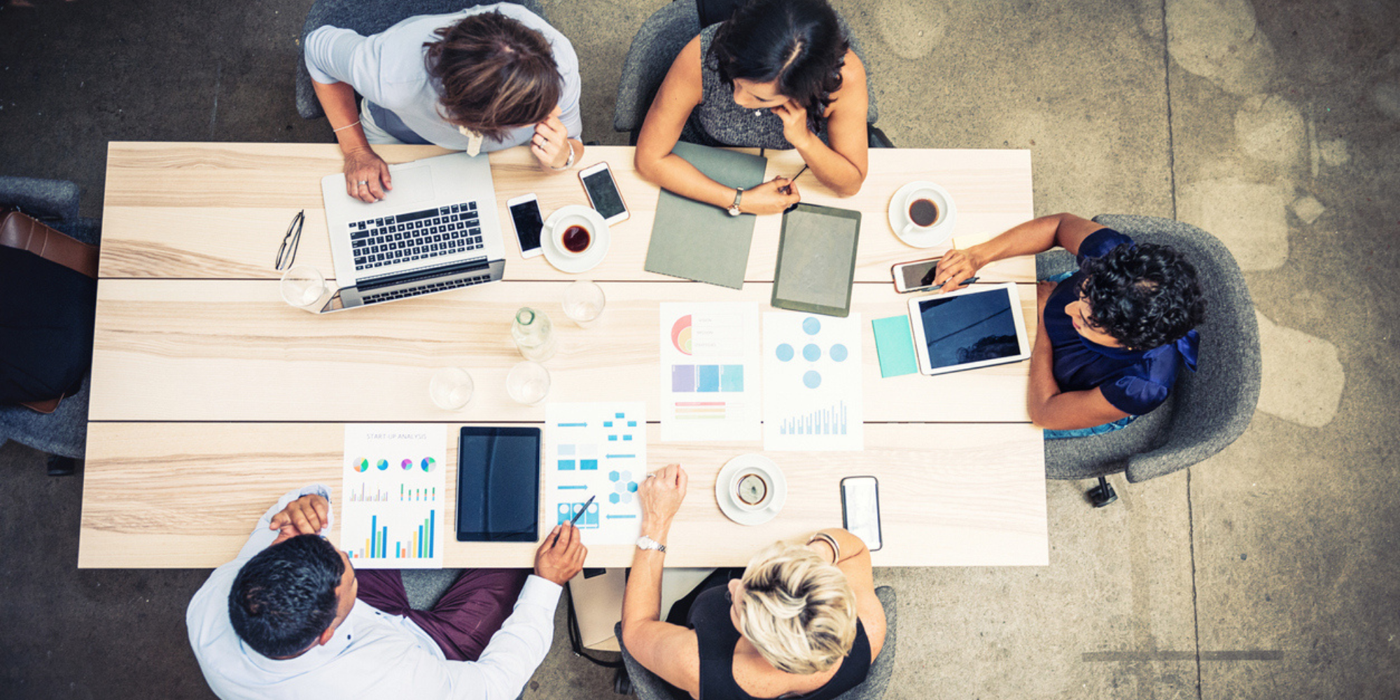 people sat around a table working and discussing graphs. ABM 